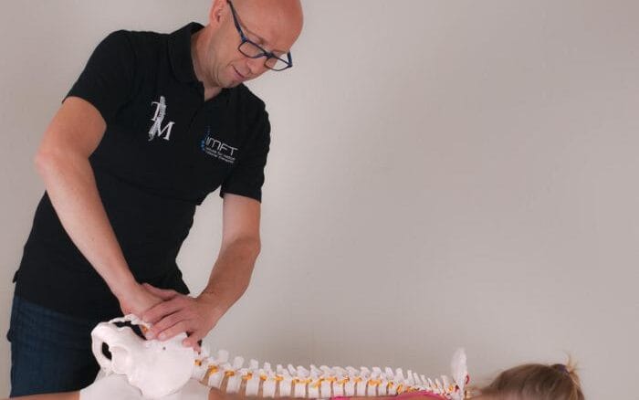 Alain Steverlynck, hoofd van de opleiding manuele therapie, voert een techniek uit op het sacrum van een menselijk skelet